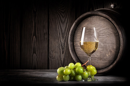 饮料木桶背景上的玻璃白葡萄酒和串玻璃白酒和串橡木庆祝的图片