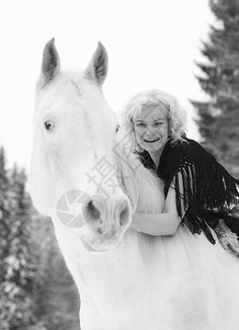 迷人的金发美女拥抱白马过冬日哺乳动物天女图片