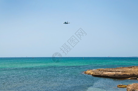 地中海在西班牙马洛卡的阳光明媚暑假日飞机从地平线海景上空坠落浪漫的丰富多彩图片