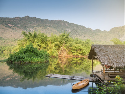 自然清晨在泰国的河上有树山和蓝天空的竹木筏皮艇旅游图片