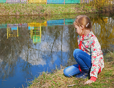 晴天小可爱的白种女孩春天坐在公园湖边的小雪人姑娘白种蓝色的图片