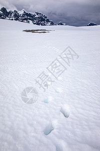 渡船小路通过深雪的足迹穿过宽阔的冰平原到南极山偏僻的图片