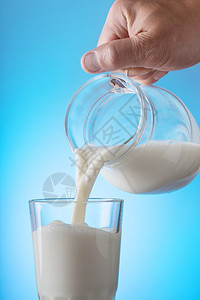 液体将牛奶从罐头倒进蓝底的玻璃杯健康天然食品的概念从瓶子倒到蓝色底面的玻璃杯里奶水从罐子倒到蓝色底面的玻璃饮料一种图片