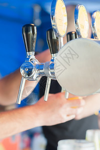 俱乐部在餐馆或酒吧供的啤里倒着一罐灌满了啤酒的手浇注图片