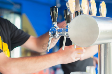 品脱在餐馆或酒吧供的啤里倒着一罐灌满了啤酒的寒冷纳达林图片