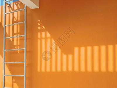 橙色建筑墙外的防火逃生处表面的薄膜阳光和遮明亮的紧急情况逃脱背景图片