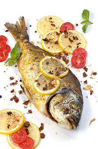 健康金黄色多拉加柠檬片和西红柿香料的烤鱼配给图片