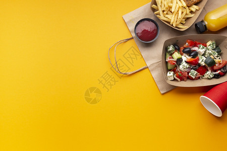 黄色餐桌上放着沙拉、番茄酱和薯条图片