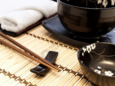 场所设置东方风格的餐桌在竹垫上用筷子服务人菜肴图片