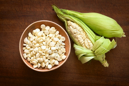 碗中的谷粒和称为Choclo西班牙语的白玉米棒子头顶照片用英语秘鲁或库斯科玉米通常在秘鲁和玻利维亚发现在自然光的木板上拍摄制的新图片