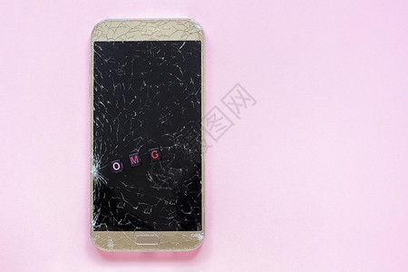 碎裂的移动电话和粉红背景文字OMG概念空间上视角复制顶端视图断裂的移动电话和文本OMG碰撞破碎的细胞图片