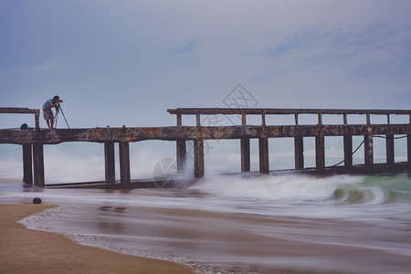 摄影师海滩三脚架在暴雨当日拍摄海滨码头的照片男子图片