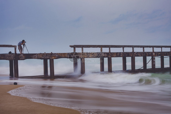 摄影师海滩三脚架在暴雨当日拍摄海滨码头的照片男子图片