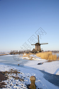 风景优美蓝色的河冬季风车有雪和蓝天空图片
