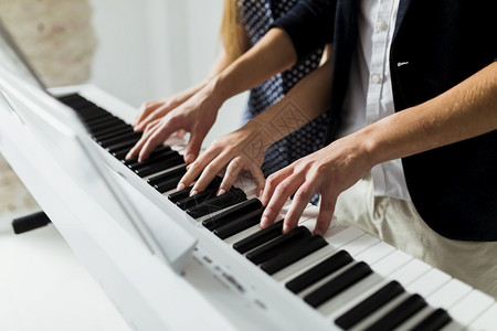 教钢琴白色的优质人们亲手演奏钢琴键盘的一对夫妇背景