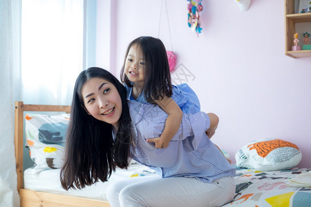快乐的亚洲小女孩在她母亲的背上在房子里微笑女士家庭图片