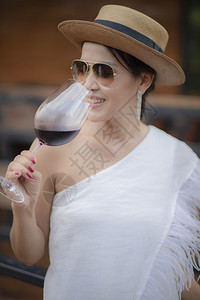 美丽的亚洲女人在酒杯中喝红玻璃活动肖像图片