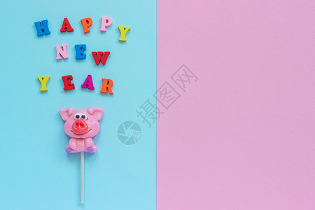 孩子东希望粉红小猪棒糖和多彩新年快乐在粉红蓝色背景上的新年喜悦画作粉红蓝底最视野复制版空间布局概念贺卡图片