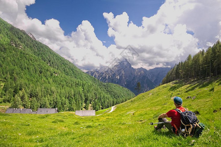 徒步旅行坐在草坪上的远足者欣赏意大利阿尔卑斯山的景色美丽背包图片