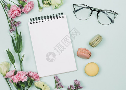 粉红色的康乃馨花在螺旋笔记本眼镜周围的花朵蓝色背景最佳靠近业务图片