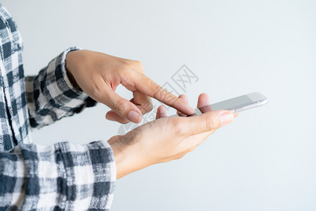 抓住保持细胞在白色背景上使用智能手机的近身女触摸移动电话屏幕的妇女手指触摸移动电话屏幕图片