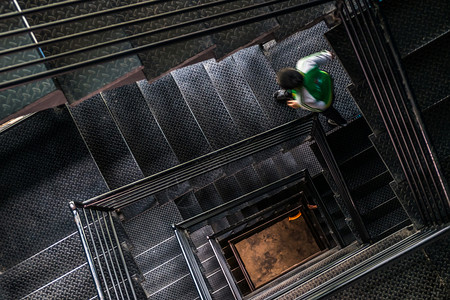 楼梯间艺术一个男人走在平方钢铁楼梯上从顶部看黑色的图片