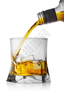 威士忌从瓶子倒到玻璃杯中冰在白色背景上隔绝的冰面威士忌从瓶子倒到有冰的玻璃杯中目立方体黄色图片