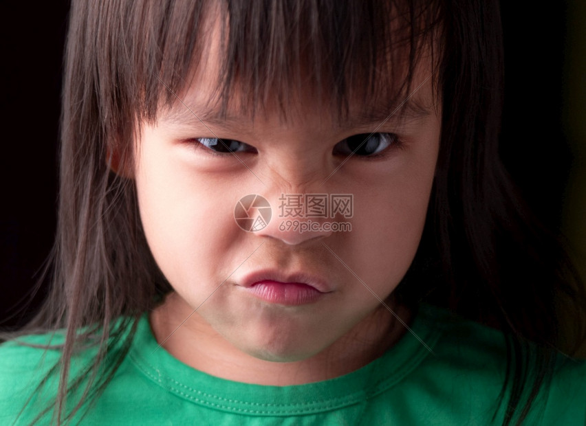 童年女亚洲小孩在黑暗背景下充满愤怒的表情长相脸部肖像图片