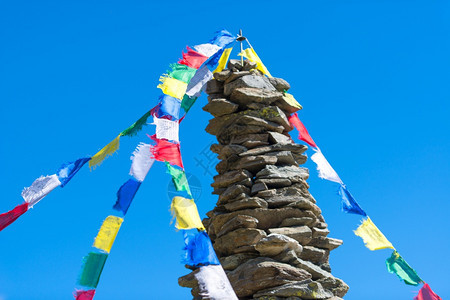 或者祈祷佛教挂在石堆或山顶高塔上蓝天背景的藏青佛祷告旗帜多彩图片