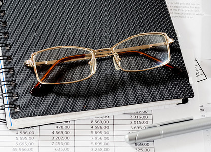 关闭一张印有眼镜的笔记本关闭一张在财务表格上贴有眼镜的笔记本事经济金融图片