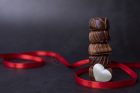 种类巧克力糖果堆叠和黑色背景的红丝带巧克力专注于诱惑可图片