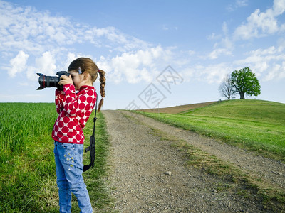 爱好水平的草年轻女孩在瑞士农村有一台大相机在拍摄风景时下照片图片