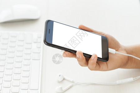 小工具将白色屏幕显示在办公桌上的手机举起技术聪明的图片