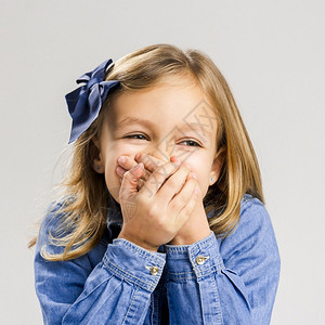 女年轻的一个害羞小女孩肖像用手遮住嘴工作室图片