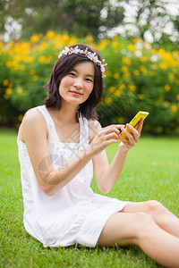 亚洲人坐着美丽的在公园使用移动智能手机的亚裔妇女可爱的高清图片素材