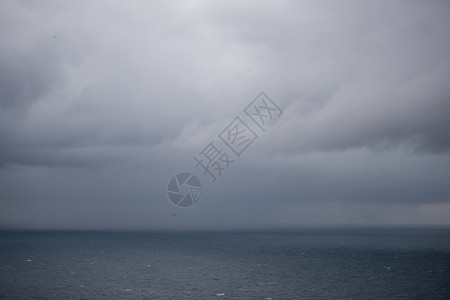 黑色的激烈海洋背景有雨云海洋背景地平线上有云和雨多的图片