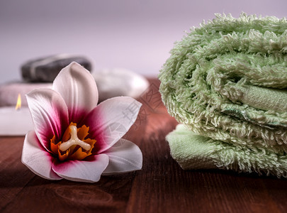 产品卷起的绿色毛巾树上的兰花和背景中石头毛巾背景中的鲜花和石头温泉背景场宁静图片