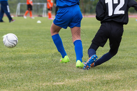 比赛中的小足球运动员守卫士和白健康男生绿色图片
