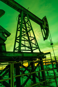 商业日落天空背景下的泵千斤顶石油提取概念泵绿色原图片