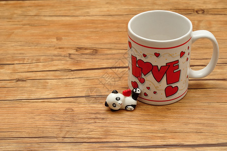 问候浪漫的庆祝情人节一个白杯子上面写着爱的词用一个拿着红心的陶瓷熊猫雕像图片