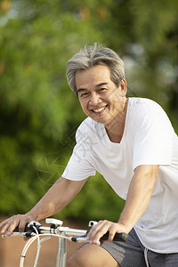 男人凉爽的在绿色公共园骑脚踏自行车时微笑着脸部的亚洲人牙运动图片