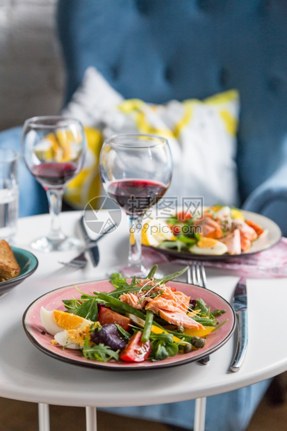 坐着白色的叉沙拉三文鱼和粉红色盘子中的蔬菜蓝椅子背景的桌上图片