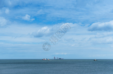 艰难的海上石油钻探地平线上海的船只平静而多云的天空地平线上的海船只石油钻井平静而多云的天空蓝色工业图片