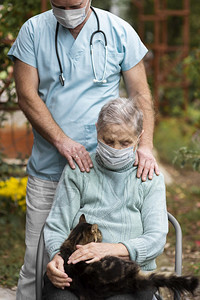 采取正面抽象的由男护士照顾有医疗面具老年妇女看病图片