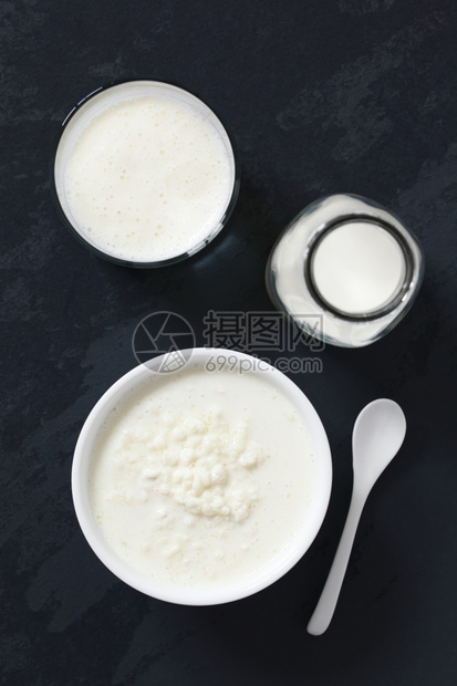 Kefir牛奶中的Kefir粒子加上奶瓶和一杯新鲜的kefir饮料用自然光选择焦点关注基fir谷物顶部和基菲尔饮料拍摄了板块上的图片