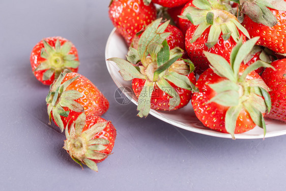 自然农场白色盘子鲜草莓在紫底彩板上红草莓和新鲜多于图片