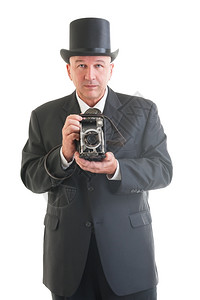 时尚陈年经典的中摄影师穿着旧式商业西装用白色隔离的反光相机拍摄图片