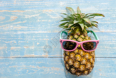 菠萝热带水果有粉红太阳眼镜蓝风木本底带色风化的阳光镜片黄色木制夏天图片