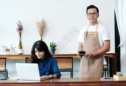 在咖啡馆小商业主食品和饮料业提供咖啡杯的年青亚洲人男士咖啡会年轻的女士店铺图片
