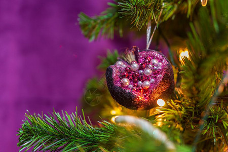 灯紧贴一棵圣诞树以紫色主题装饰并有突出的紫色石榴悬吊装饰快乐的魔法图片